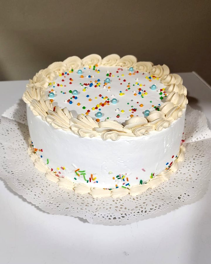 Torta tradicional cubierta con chantilly, con rosetones en el borde y grajeas de colores encima