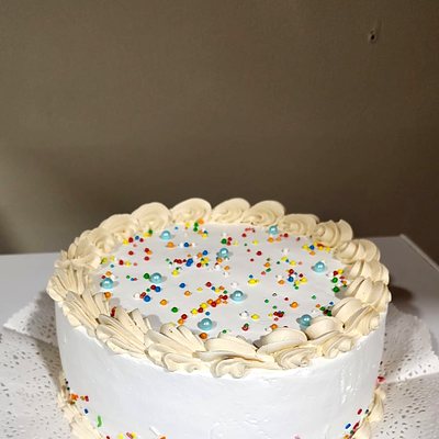Rosetones de chantilly y grajeas de colores sobre la torta, de cerca